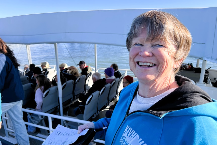 A smiliing woman next to a tourist boat