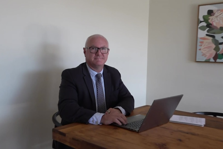 Tim Lawless sitting at a desk with a laptop.