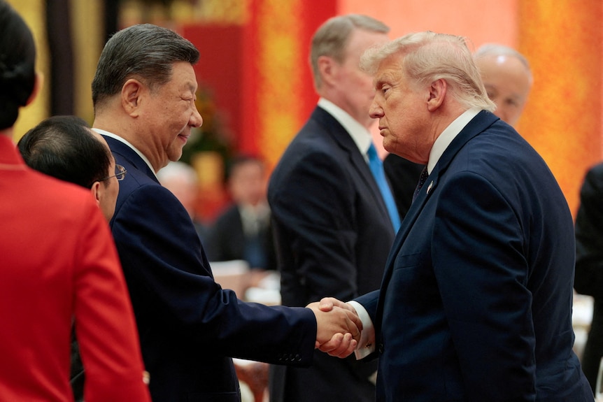 Two men wearing suits shake hands.