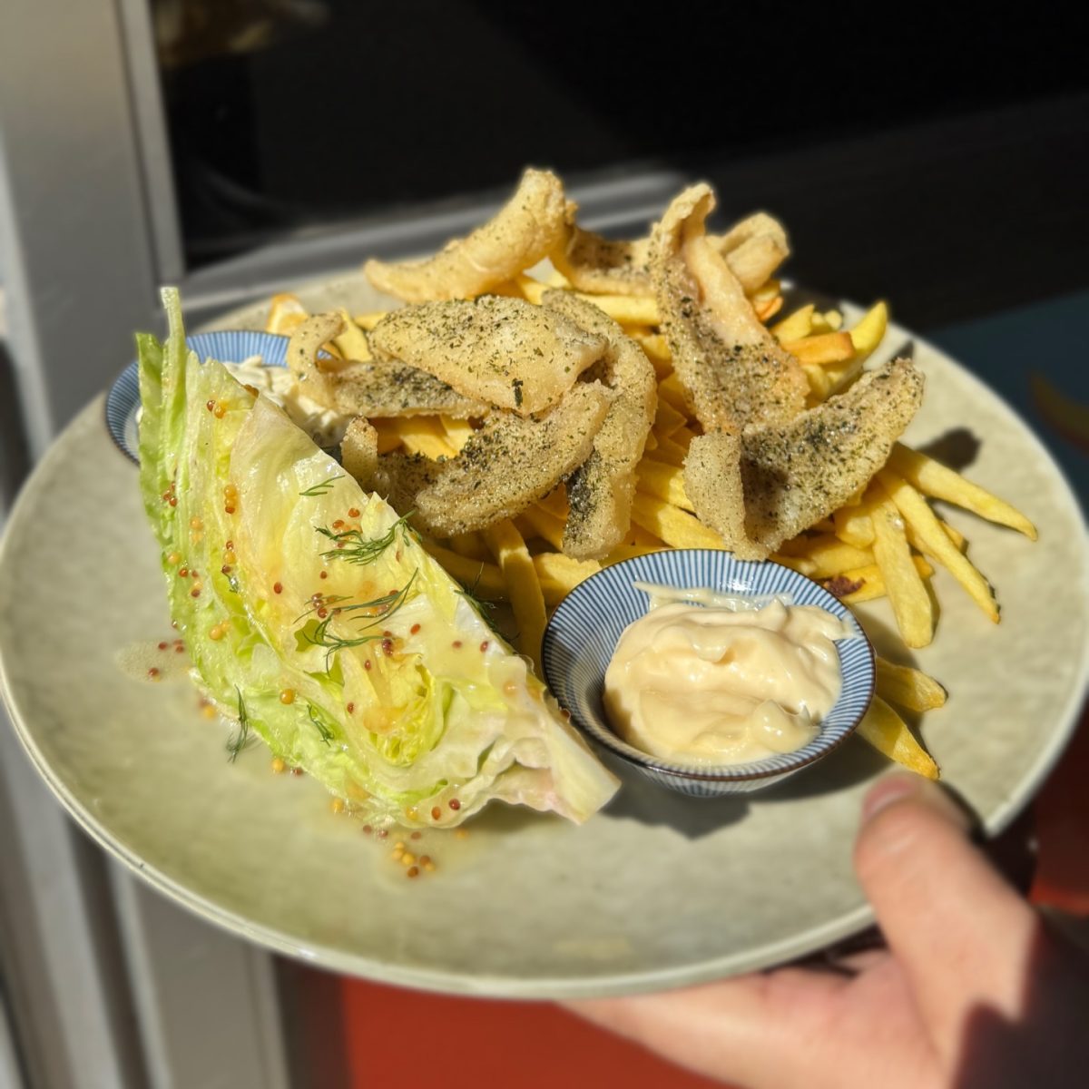 A plate of fish and chips with a wedge of lettuce.