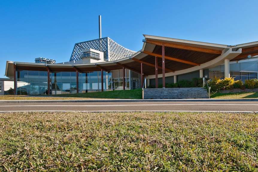 An outside view of a large building with curved exterior and a cage structure on top.