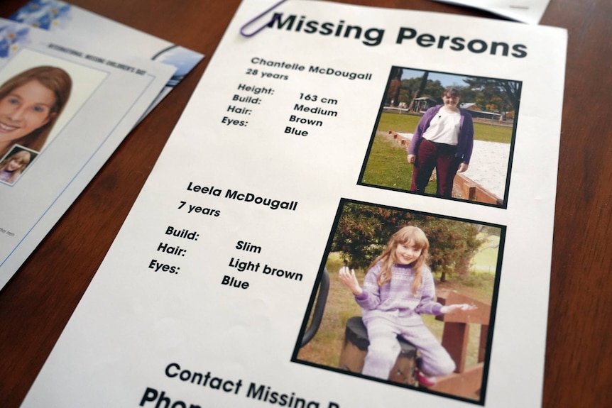 A missing person flyer, showing images of Chantelle McDougall and her daughter Leela, lays on a table.