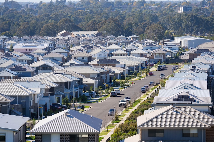 An aerial view of a new housing suburb with newly built homes and cars parked on streets.