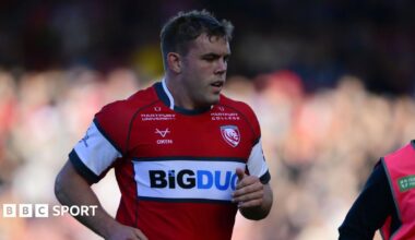 Jack Singleton jogging on the pitch during a match, he is wearing red Gloucester rugby kit
