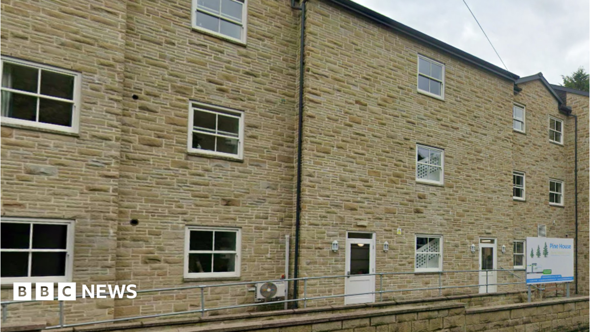 A large sandstone brick building with a white sign reading Pine House.