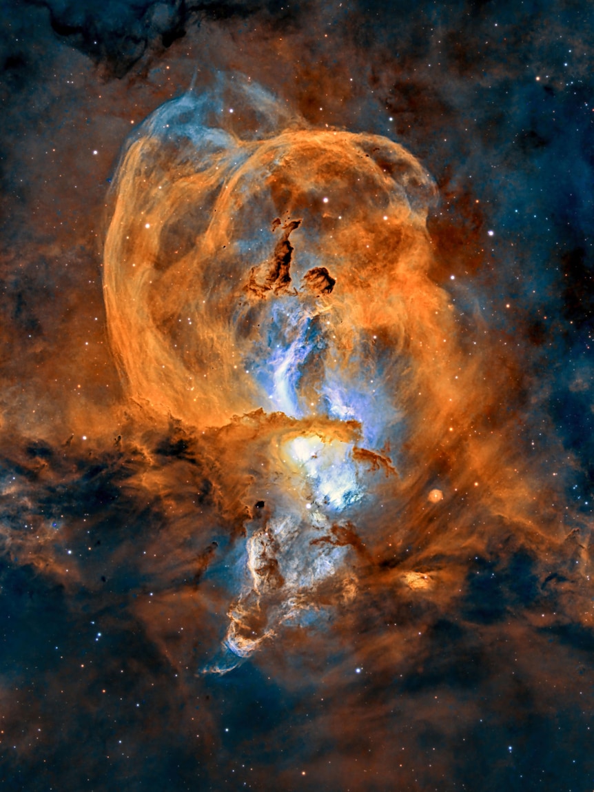 A deep-space photo of a yellow and blue nebula resembling the Statue of Liberty.