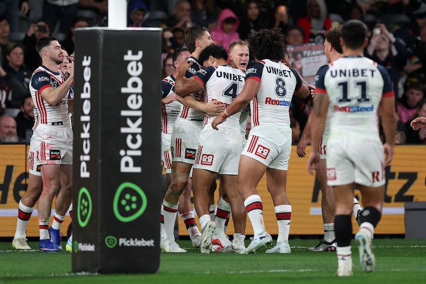 A group of players celebrate scoring a try