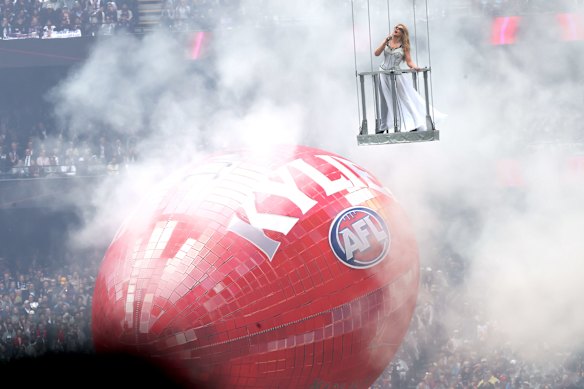 Kylie floats above the MCG surface, and a giant glittery Sherrin, as she performs at the AFL grand final.