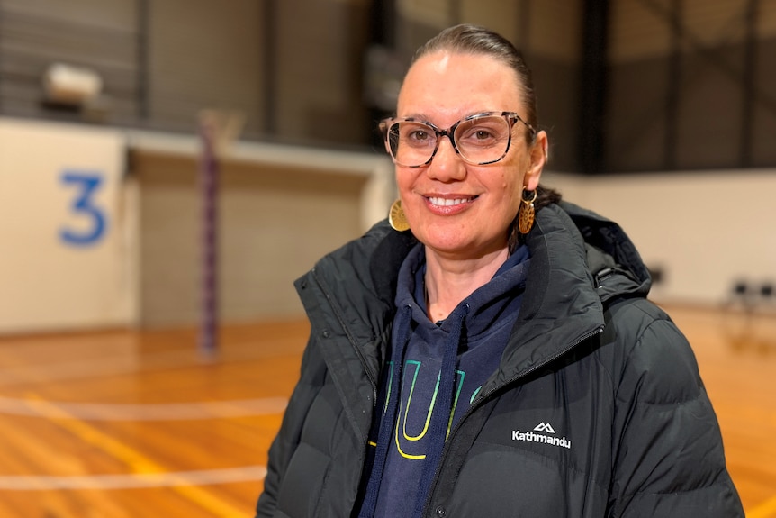 Netball executive Ali Tucker-Munro smiles at the camera, she wears a black puffer jacket