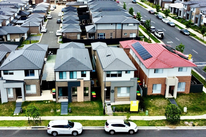 Aerial shot of dozens of houses in neat rows in a new outer-suburban housing estate.
