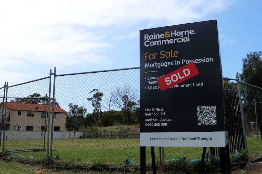 A for sale sign in front of vacant land