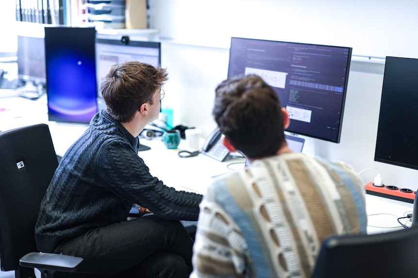 Two men look at a computer sifting through complex data about bloodwork.