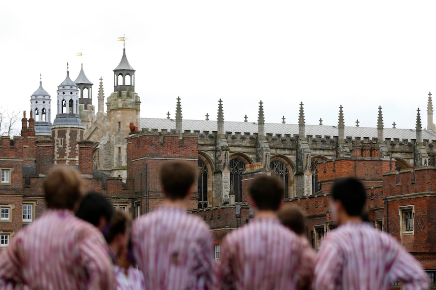 A group of jersey-wearing men stand in front of a spired building.