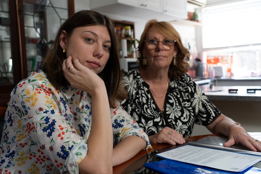 Two women, a mother and daughter, at a table with documents in front of them.