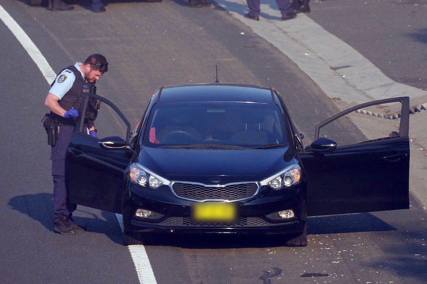 a police officer inspects a car that was hijacked in sydney and female driver thrown out
