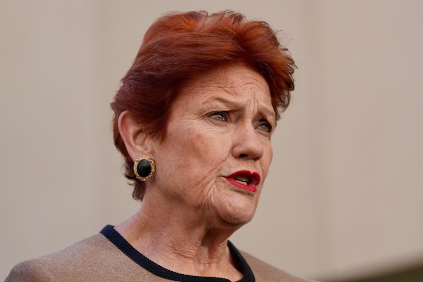 A woman with red hair, red lipstick and black and gold earrings