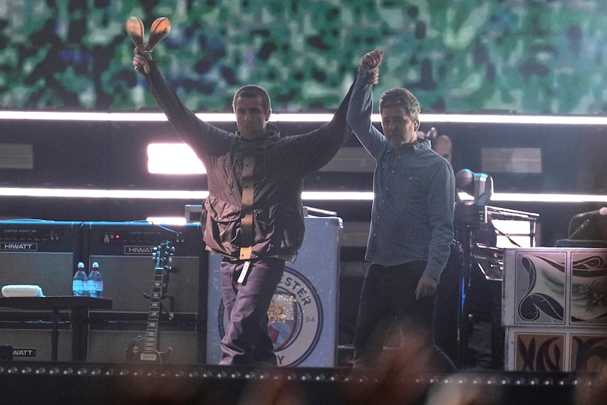 The Gallagher brothers hold each other's hand aloft while on stage