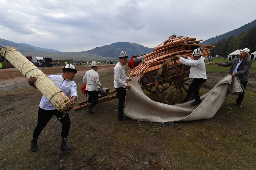 people carry parts of a yurt.