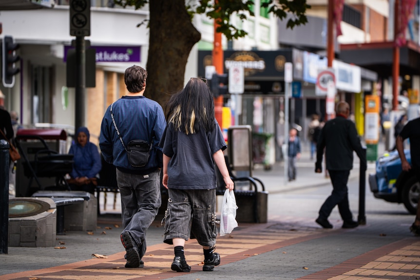 Two people walk through Hobart's Elizabeth Street mall holding shopping bags.