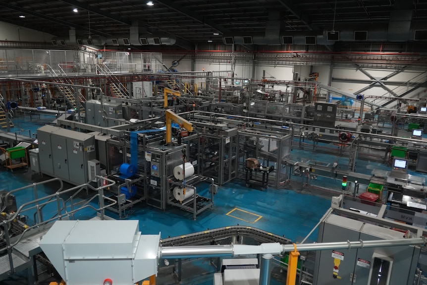 A series of conveyor belts and stainless steel machines inside a factory.