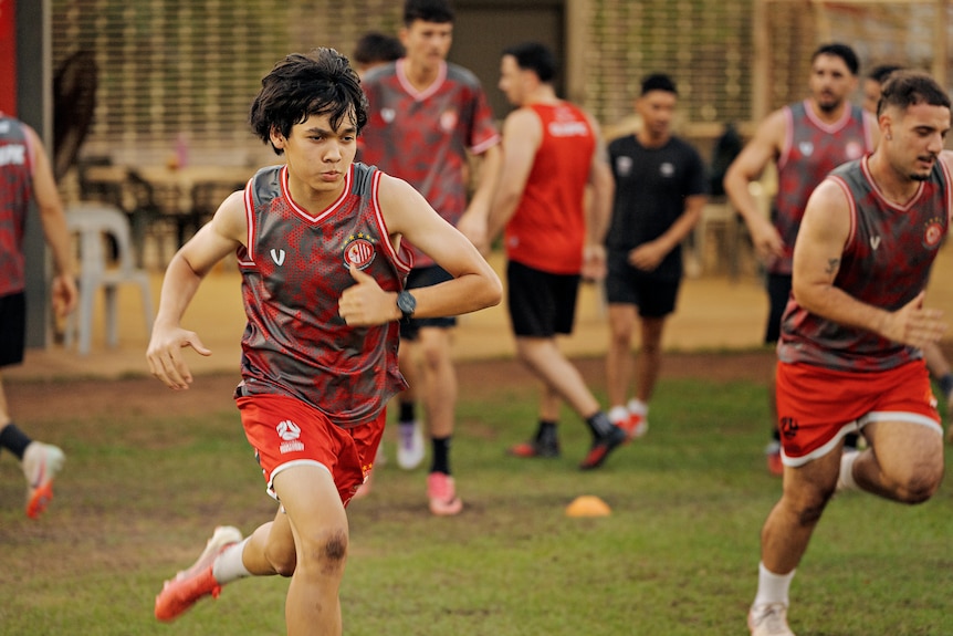 Mark O'Connor runs toward the camera during football training, with other players behind him.