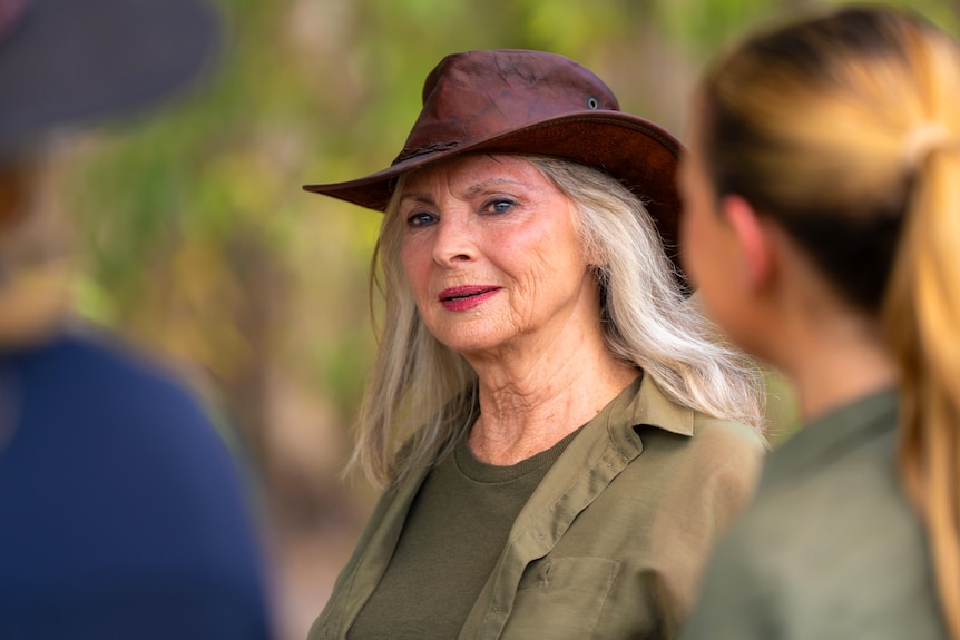 Delvene Delaney wearing a broad brimmed brown hat and a dark green shirt looks to he right