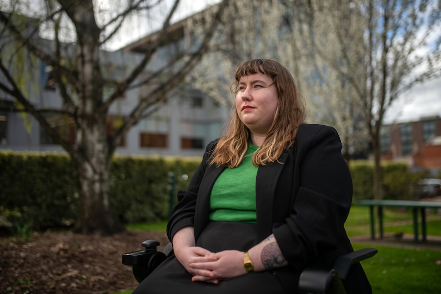 A woman sitting in a wheelchair with a green shirt.