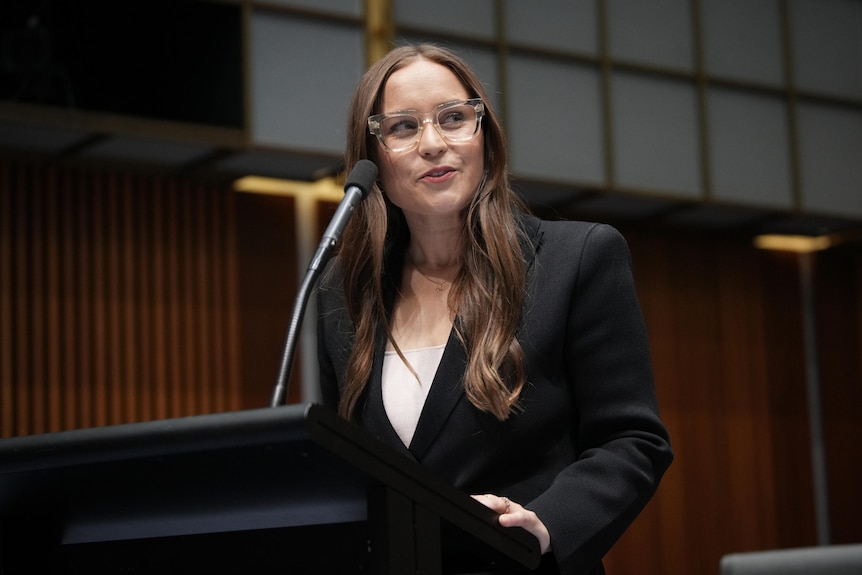 A white woman in a suit at a lectern 