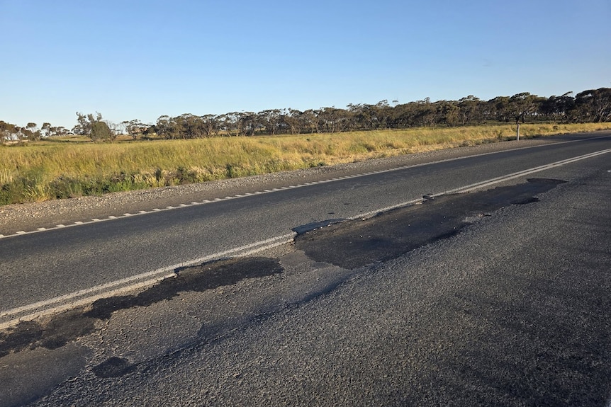 A degraded bitumen road in the countryside.