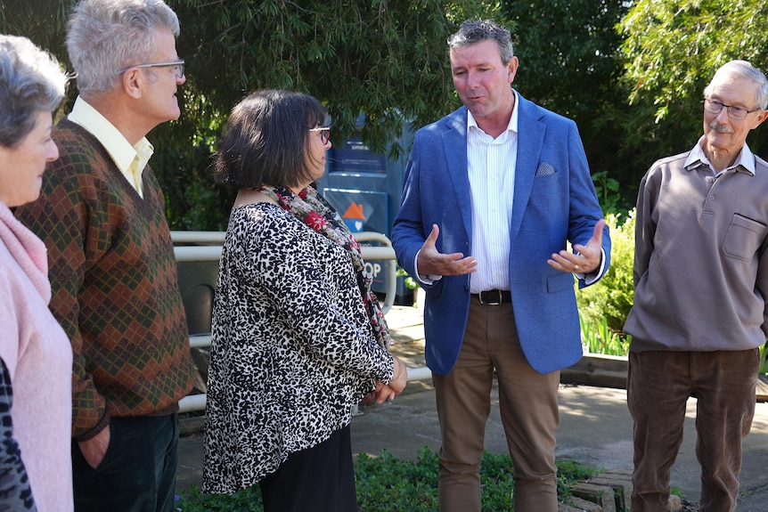 A group of people talking in front of a garden