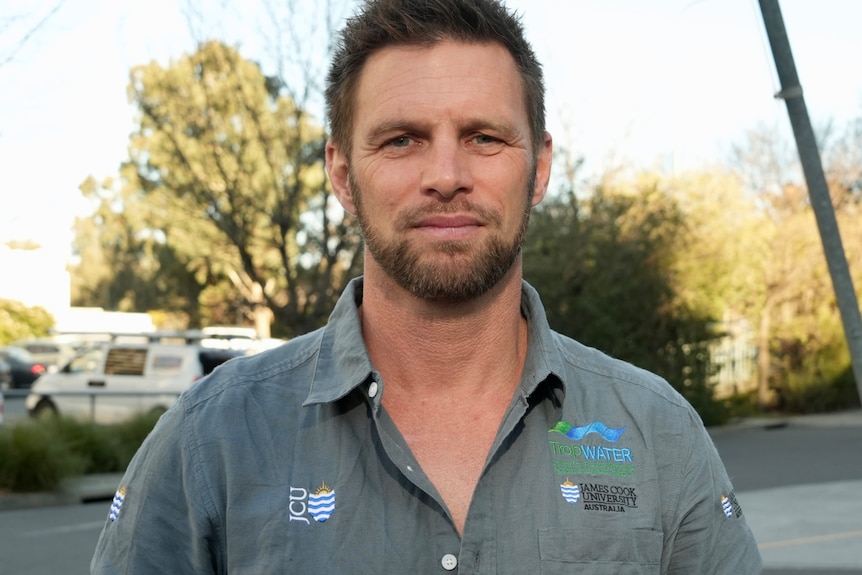 Chris Cleguer with short brown hair and facial hair, wears a khaki green shirt, looking front on at the camera