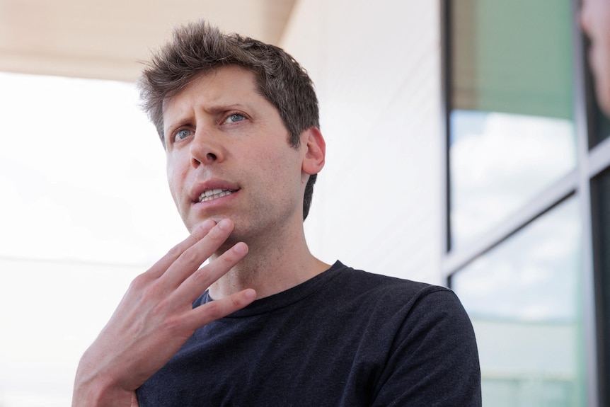 Sam Altman with his hand up to his chin, looking thoughtful.