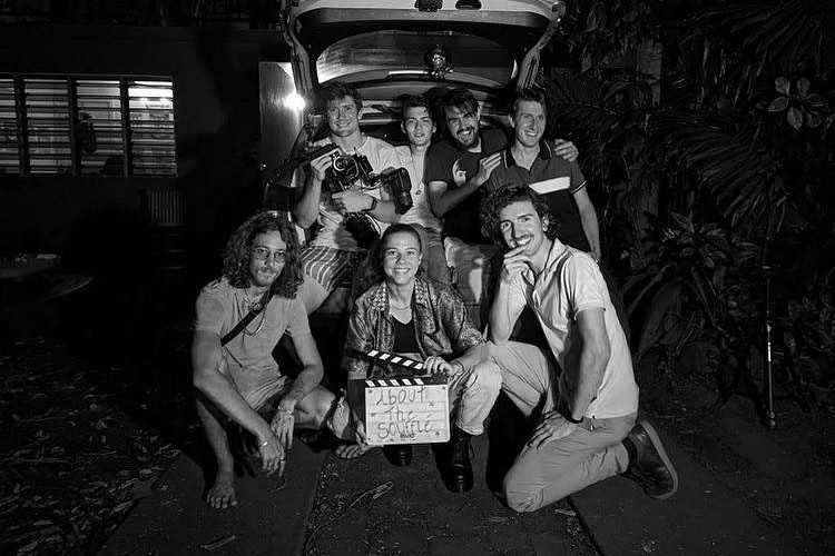 A group of people pose by a car