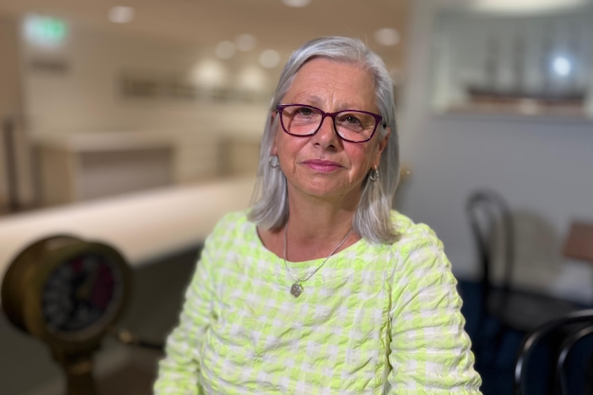 A woman with glasses and a green shirt looking at the camera