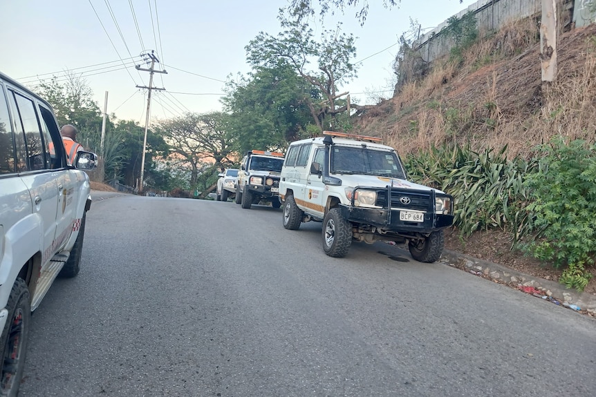 Four police vehicles are parked on the side of a road.