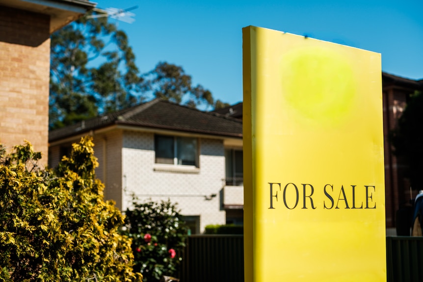 Bright signs in front of properties saying 'For Sale'