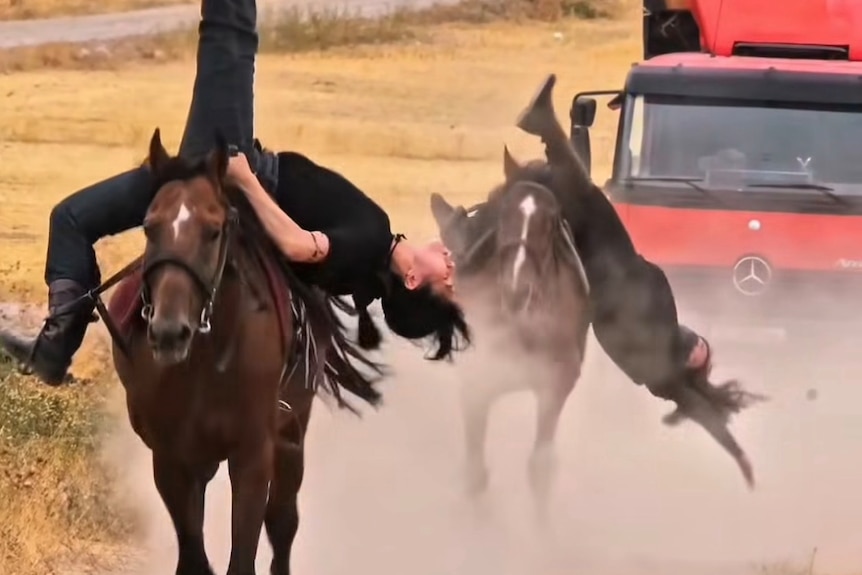 two women upside down on horses.