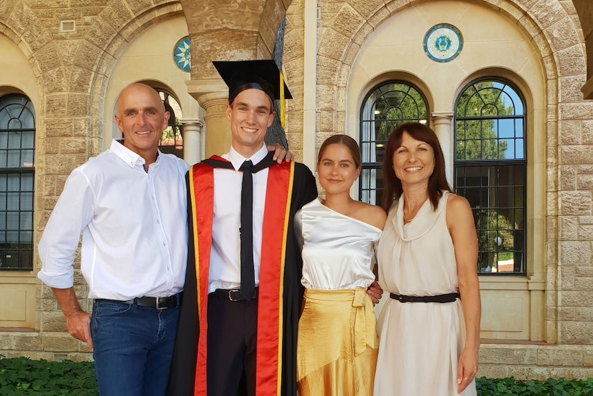 Greg stands with family members on a university graduation day