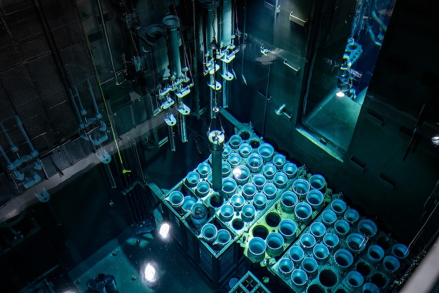A thin cyclinder of silver silicon is lowered into white tubes.
