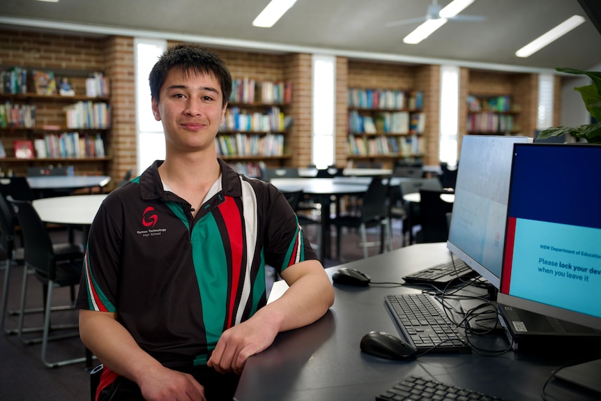 A high school aged male sitting in a school library