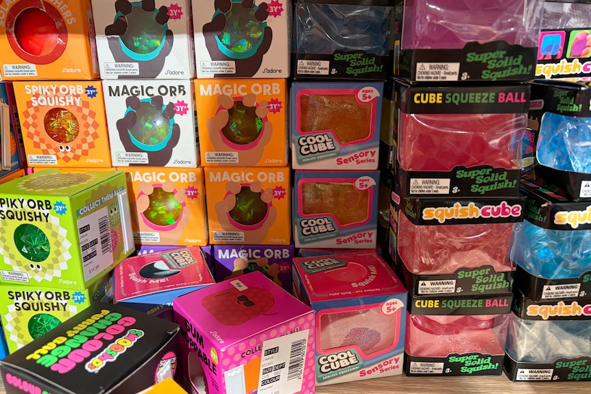 Boxes of small squishy cubes stacked on a store shelf.
