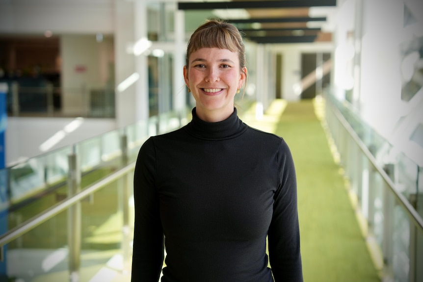 a woman in a dark top on a walkway smiling