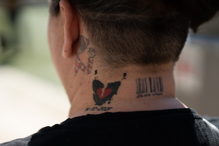 A broken heart tattoo on a woman's neck.
