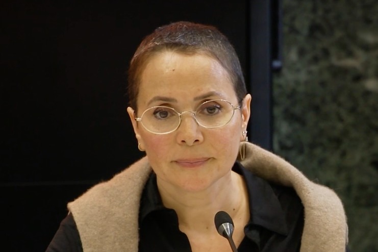 A woman looks on with a serious expression on her face.