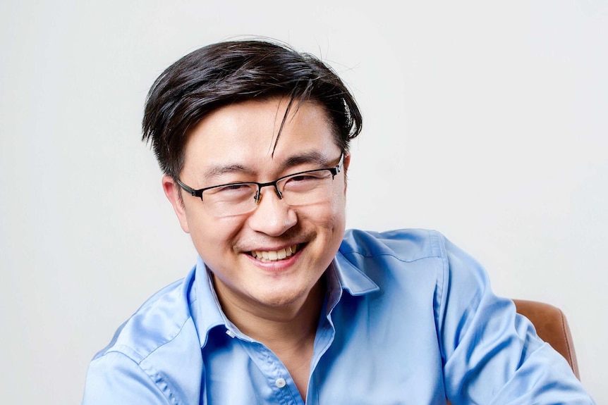 A man sits on a chair and smiles.