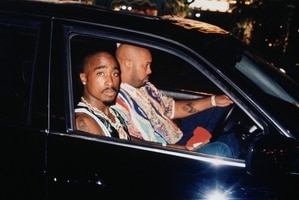 Two men look solemn in a black BMW.