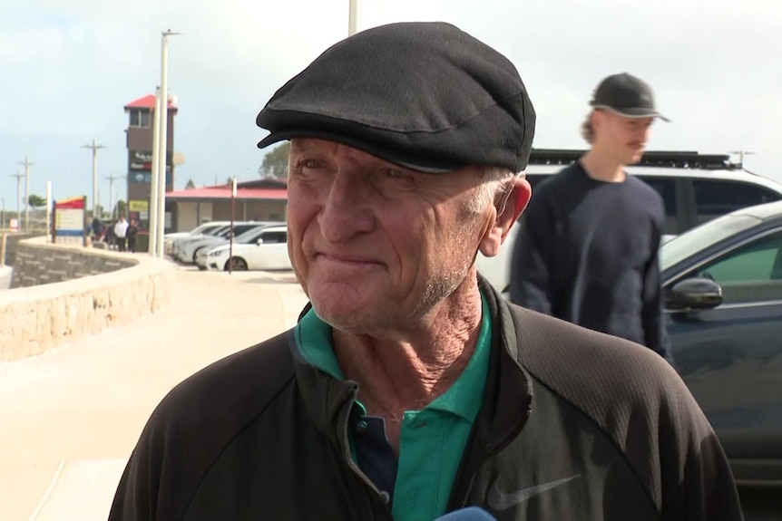 A older man wears a beret at the beach