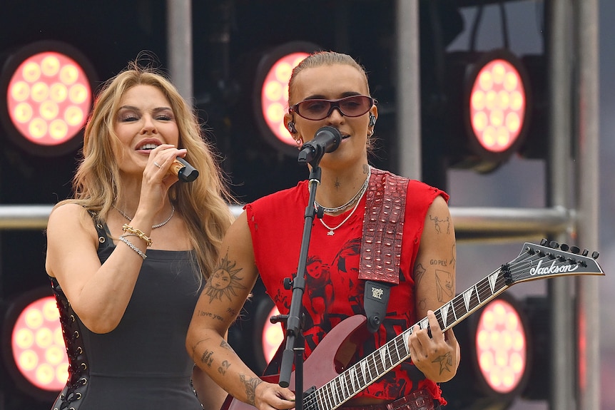 Kylie Minogue wearing black and G Flip wearing red and playing a guitar