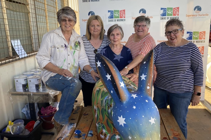 five women stand behind a painted cement bilby