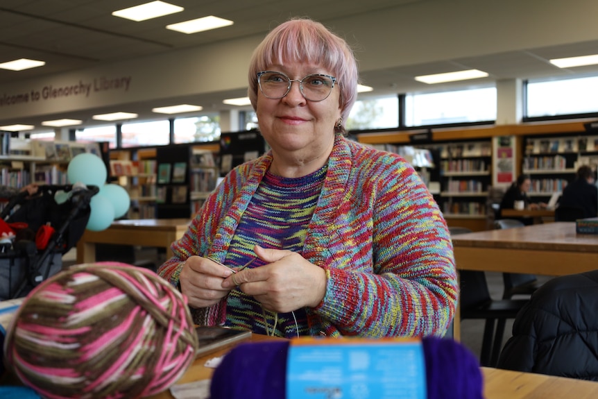 Irina Bridges wears a hand knitted top and a hand-knitted cardigan both made from different multi-coloured yarn.